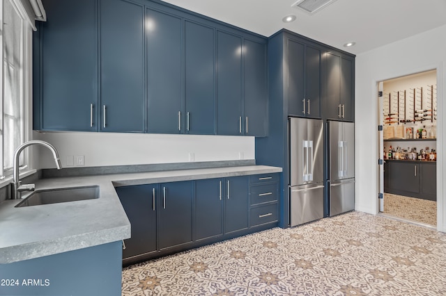 kitchen with blue cabinets, high end fridge, and sink