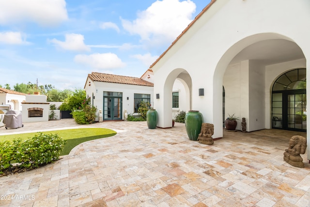 back of property with a fireplace, french doors, and a patio