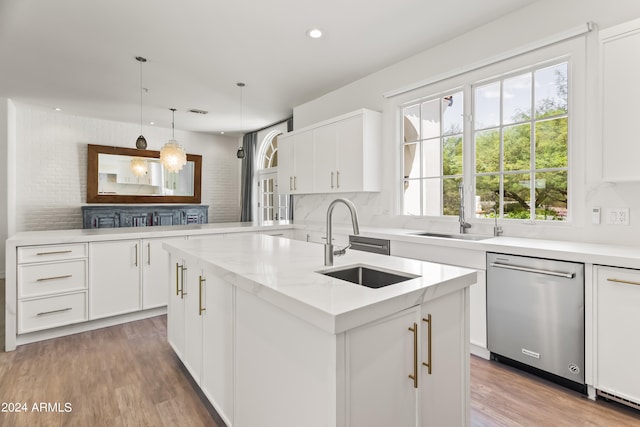 kitchen featuring dishwasher, pendant lighting, white cabinets, and a center island with sink