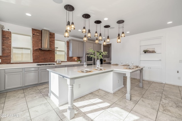 kitchen with gray cabinetry, a spacious island, wall chimney exhaust hood, and a breakfast bar area