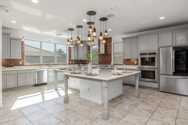 kitchen with stainless steel appliances, tasteful backsplash, a kitchen bar, gray cabinets, and a kitchen island