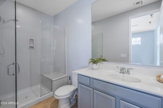 bathroom featuring tile patterned floors, a shower with door, vanity, and toilet