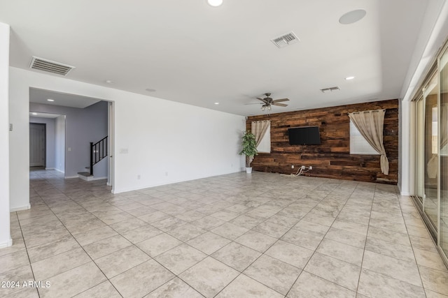 unfurnished living room featuring wood walls and ceiling fan