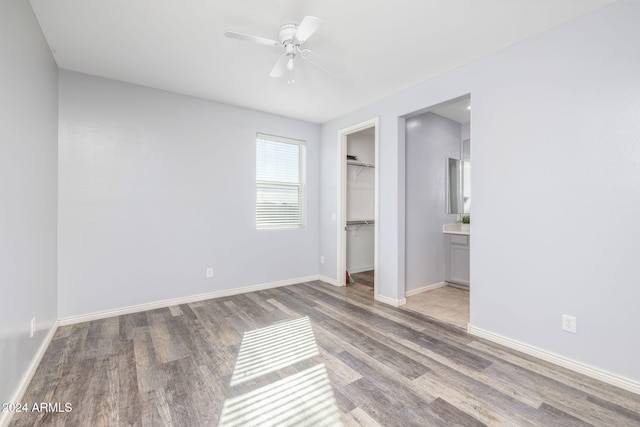 unfurnished bedroom featuring light hardwood / wood-style flooring, a spacious closet, a closet, and ceiling fan