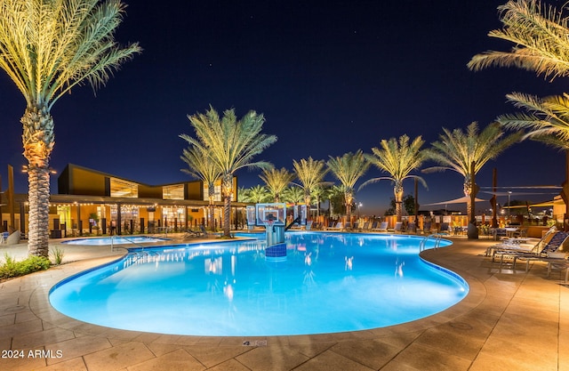 pool at night featuring a patio