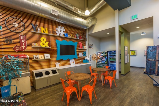 recreation room featuring a towering ceiling and dark hardwood / wood-style floors