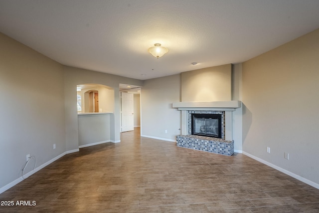 unfurnished living room featuring a tile fireplace and hardwood / wood-style flooring