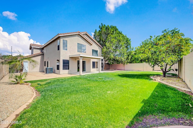 rear view of property with stucco siding, a lawn, a fenced backyard, and a patio area