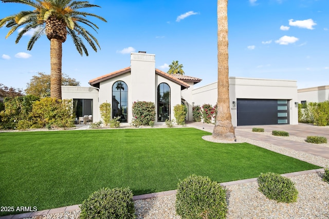 view of front of property with driveway, a garage, a chimney, a front yard, and stucco siding