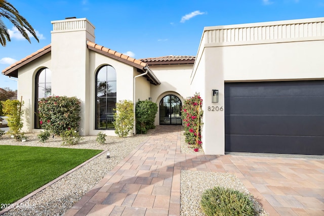 mediterranean / spanish house featuring a tiled roof, an attached garage, and stucco siding