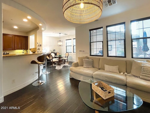 living room with dark wood-type flooring, sink, and a chandelier