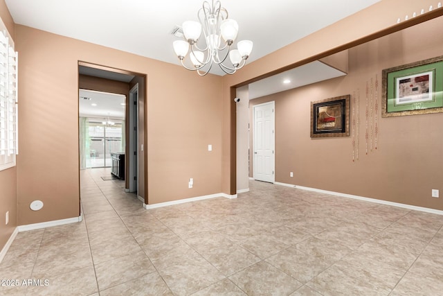 tiled spare room with an inviting chandelier