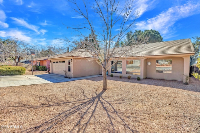 ranch-style house featuring stucco siding, a tiled roof, concrete driveway, and a garage