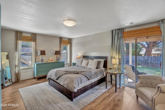 bedroom with visible vents, light wood finished floors, and access to outside