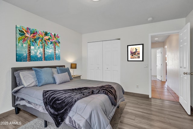 bedroom featuring a closet, baseboards, and wood finished floors