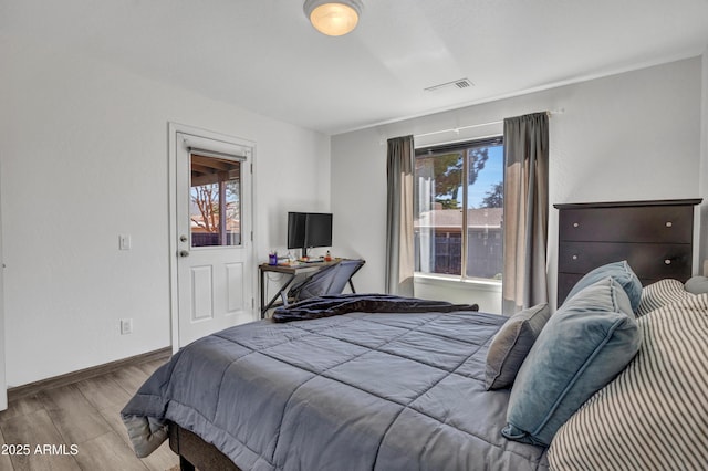 bedroom featuring visible vents, multiple windows, baseboards, and wood finished floors