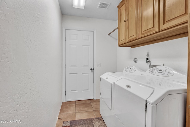 clothes washing area with light tile patterned floors, visible vents, separate washer and dryer, cabinet space, and a textured wall