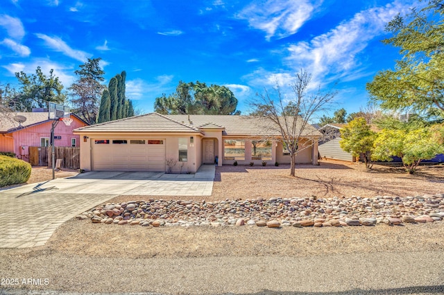 ranch-style home featuring fence, stucco siding, concrete driveway, a garage, and a tiled roof