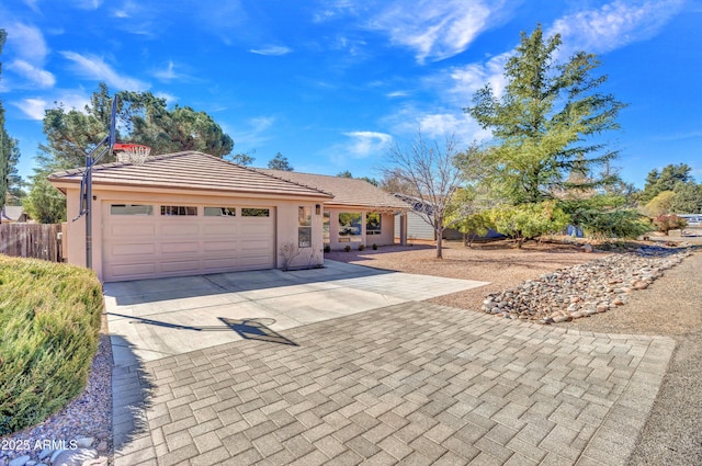 ranch-style home featuring stucco siding, a tile roof, fence, concrete driveway, and an attached garage