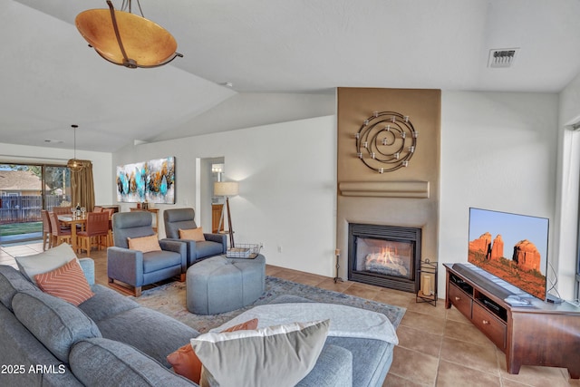 living room with light tile patterned floors, visible vents, a fireplace, and vaulted ceiling