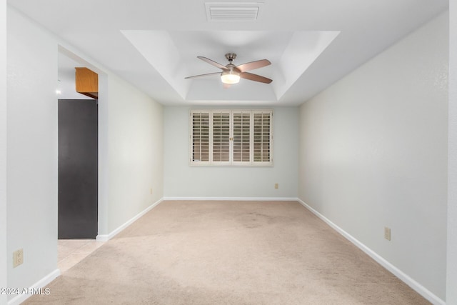 carpeted empty room with a raised ceiling and ceiling fan