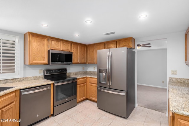 kitchen featuring light carpet, stainless steel appliances, light stone counters, and ceiling fan