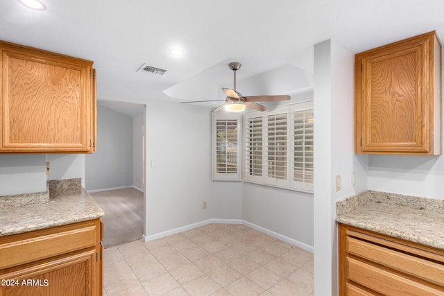 kitchen featuring light stone countertops, ceiling fan, and light carpet