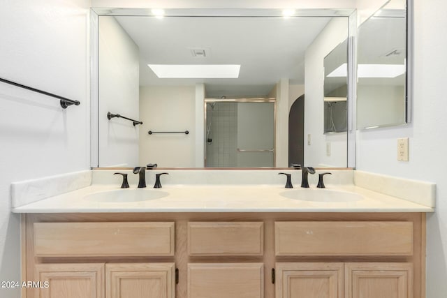 bathroom with vanity, a shower with shower door, and a skylight