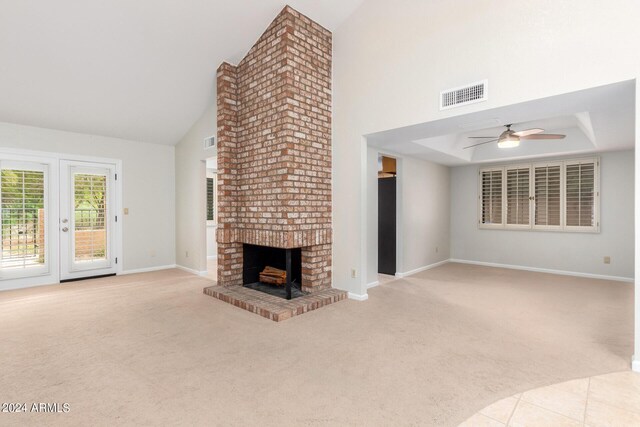 unfurnished living room with a fireplace, light carpet, a towering ceiling, and ceiling fan