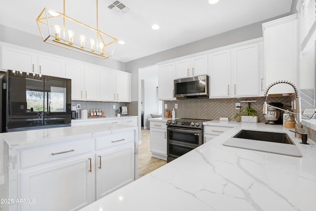 kitchen with sink, decorative light fixtures, white cabinets, light stone countertops, and stainless steel appliances