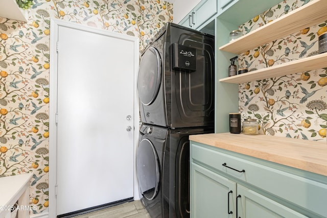 clothes washing area with cabinets and stacked washer / drying machine