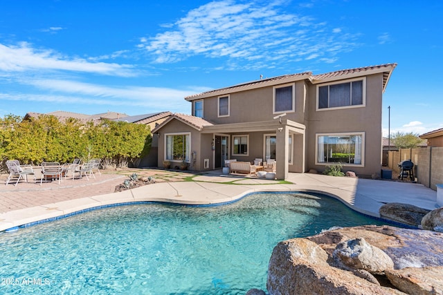 rear view of property with a fenced in pool, a patio, and outdoor lounge area