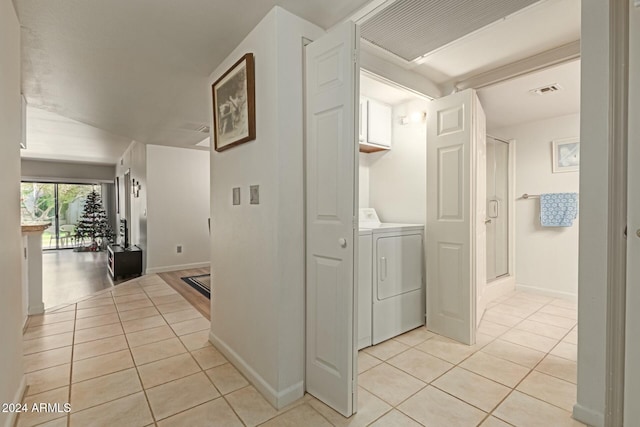 hall with washer and clothes dryer and light tile patterned floors