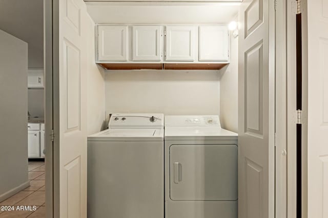 washroom featuring washer and dryer, cabinets, and light tile patterned floors