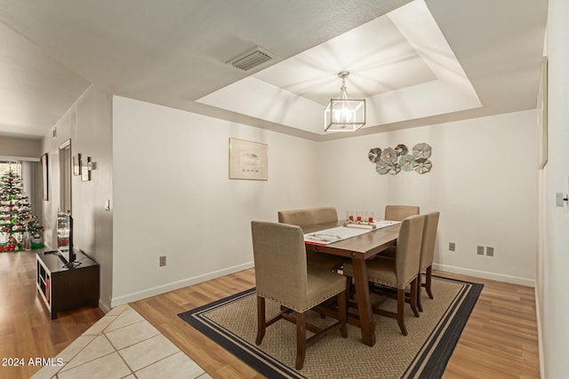 dining room with wood-type flooring and a tray ceiling