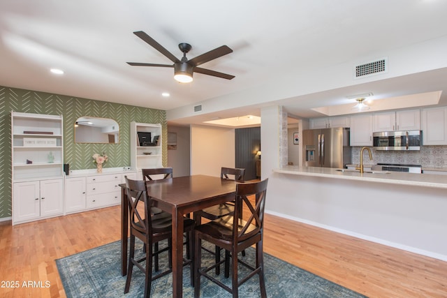 dining room featuring baseboards, visible vents, and light wood-style floors