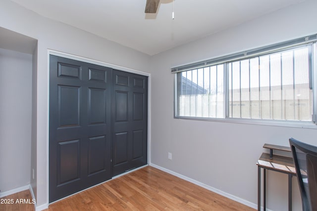 bedroom with baseboards, a closet, light wood finished floors, and ceiling fan