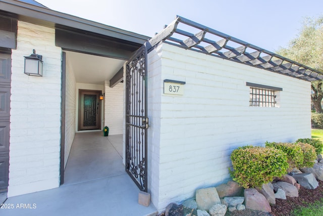 entrance to property featuring brick siding, a patio, and a garage