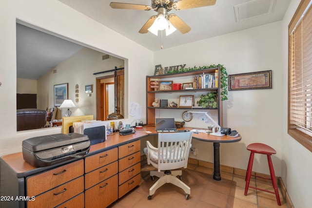 tiled home office featuring lofted ceiling, ceiling fan, and a barn door