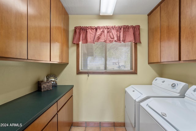 laundry room with washer and dryer, cabinets, and light tile floors