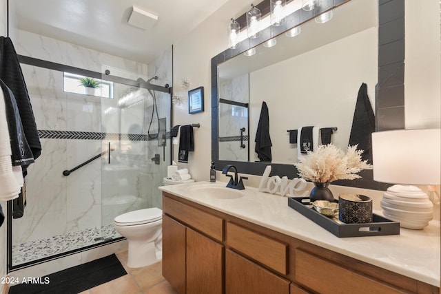 bathroom featuring a shower with door, vanity, toilet, and tile flooring