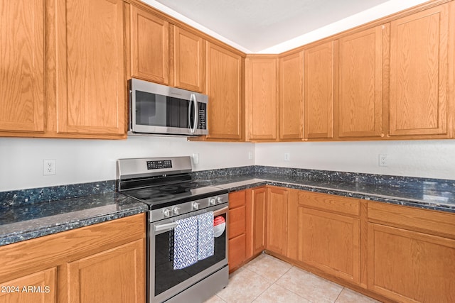 kitchen with dark stone counters, appliances with stainless steel finishes, and light tile patterned floors