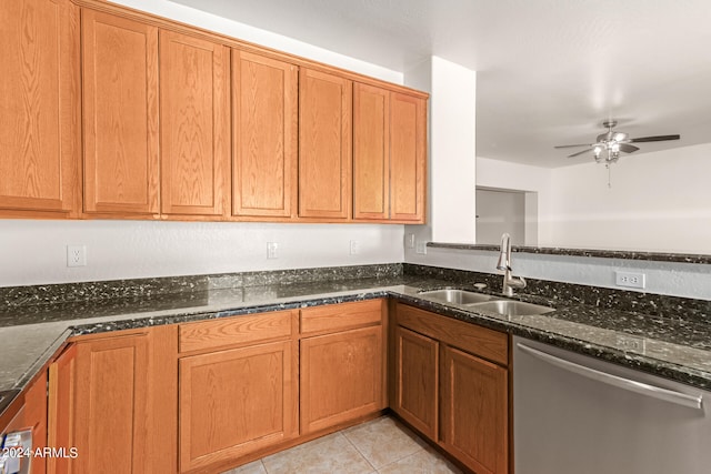 kitchen with dark stone counters, light tile patterned flooring, sink, ceiling fan, and stainless steel dishwasher