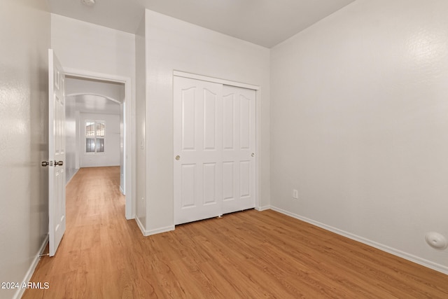 unfurnished bedroom with light hardwood / wood-style flooring and a closet