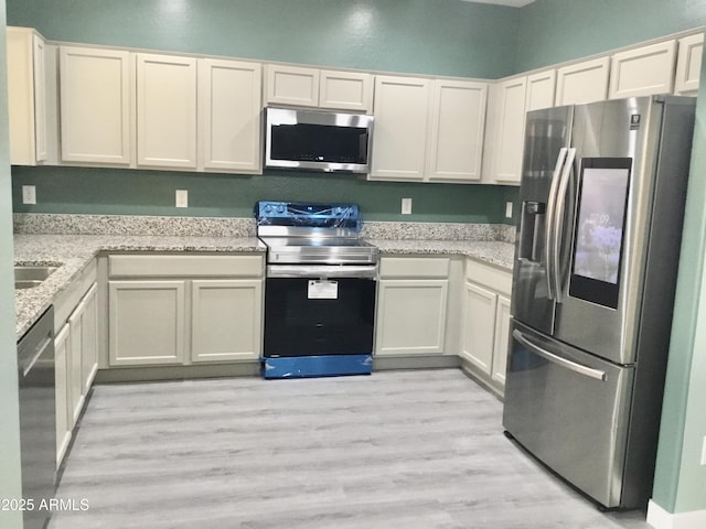 4722 S 238th Ln, Buckeye, AZ 85326 - kitchen featuring appliances with stainless steel finishes, light wood-style flooring, light stone countertops, and white cabinets