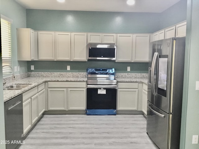 4722 S 238th Ln, Buckeye, AZ 85326 - kitchen with appliances with stainless steel finishes, a sink, light wood-style floors, light stone counters, and recessed lighting