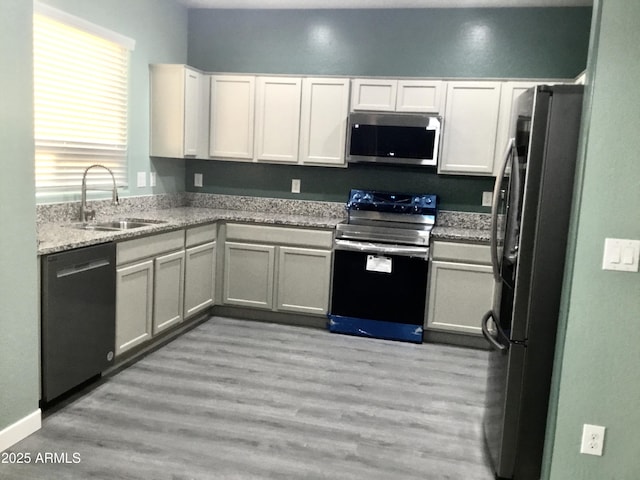 4722 S 238th Ln, Buckeye, AZ 85326 - kitchen featuring appliances with stainless steel finishes, a sink, white cabinets, light stone counters, and light wood-style flooring