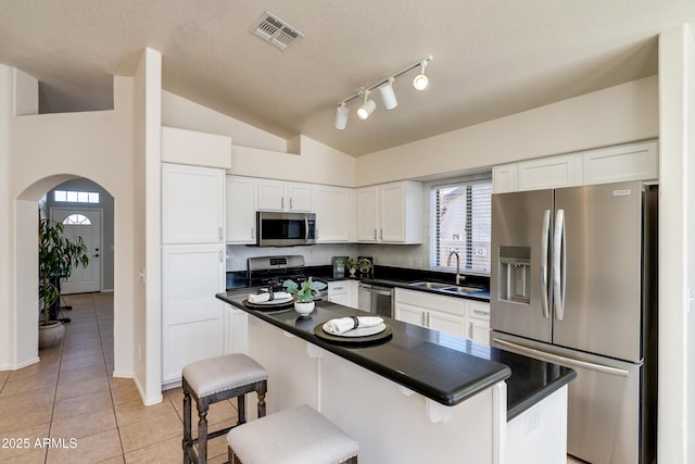 kitchen with stainless steel appliances, white cabinetry, sink, and a breakfast bar area