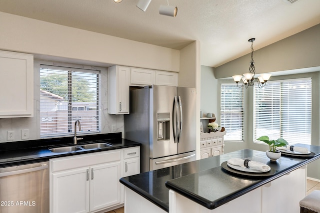 kitchen with vaulted ceiling, appliances with stainless steel finishes, sink, and white cabinets