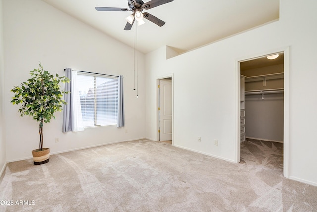 unfurnished bedroom featuring light carpet, a spacious closet, high vaulted ceiling, and ceiling fan